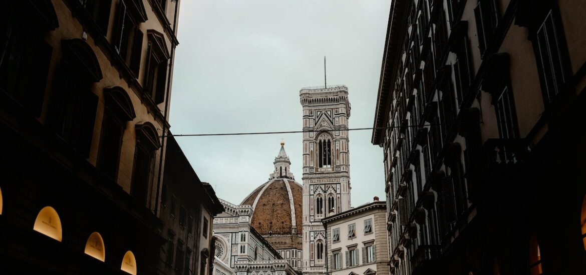 Pedestrian street lined with multi-story buildings leading to a large red-domed cathedral