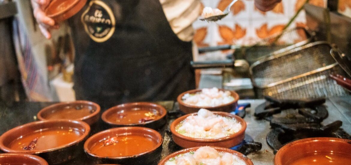 Shrimp cooking in individual terra cotta dishes on a grill