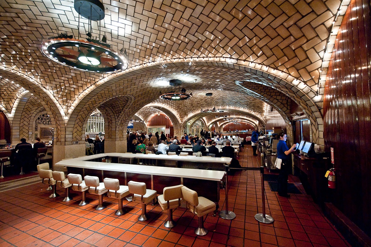 Dimly lit dining room with long tables, many chairs and vaulted cielings