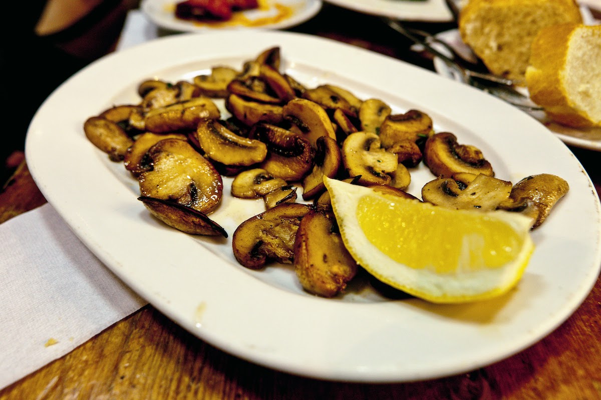 Plate of grilled mushrooms served with a lemon wedge.