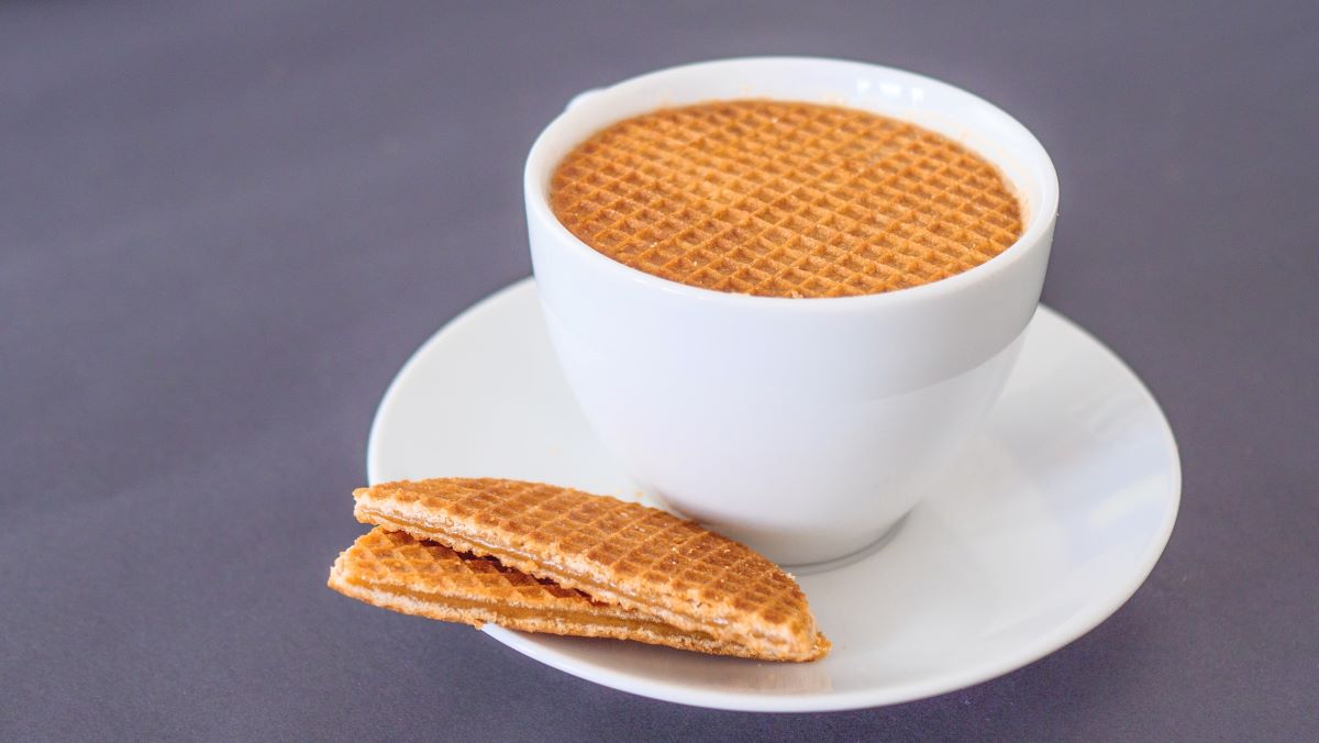 tea cup with a stroopwafel beside and inside of it. 