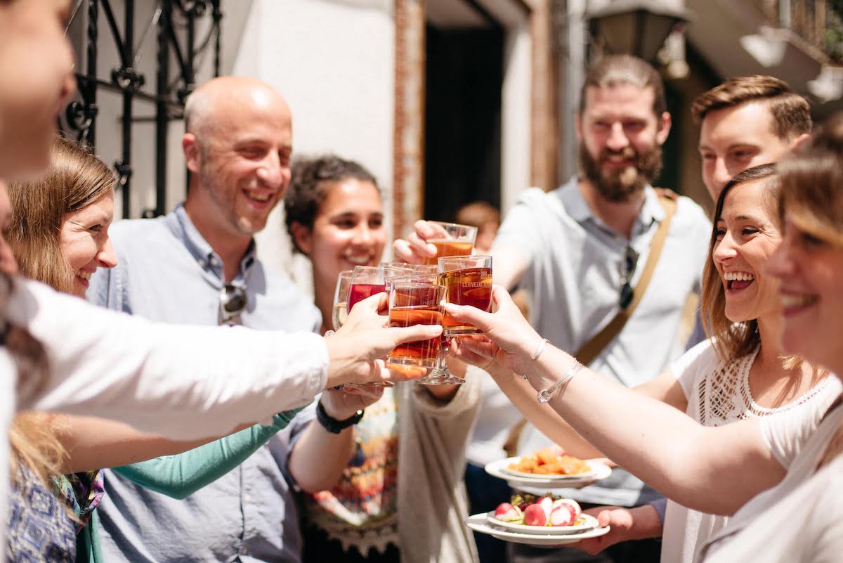 Group of people smiling and toasting with drinks.