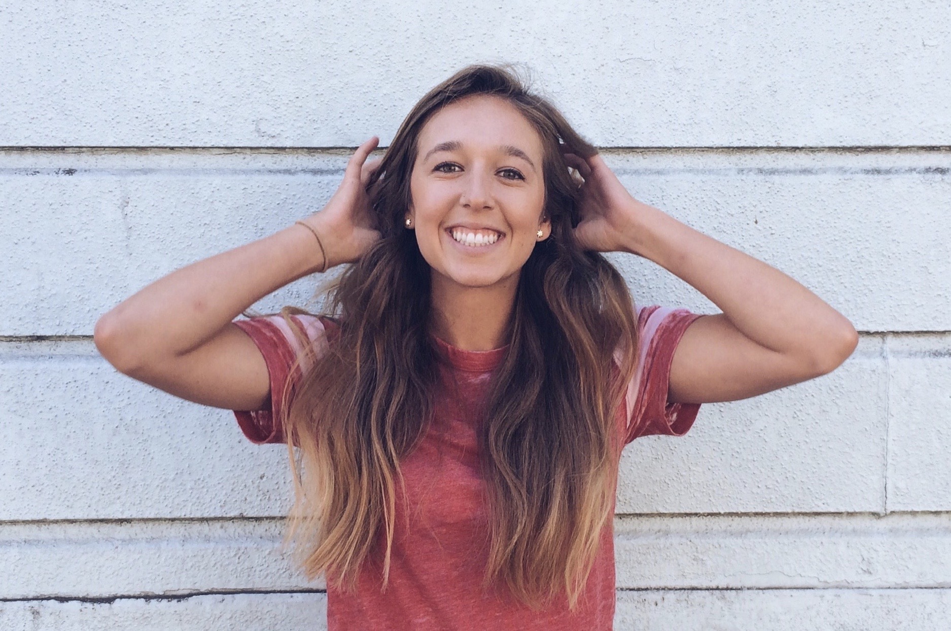 Photo of girl smiling with hands behind head and hair