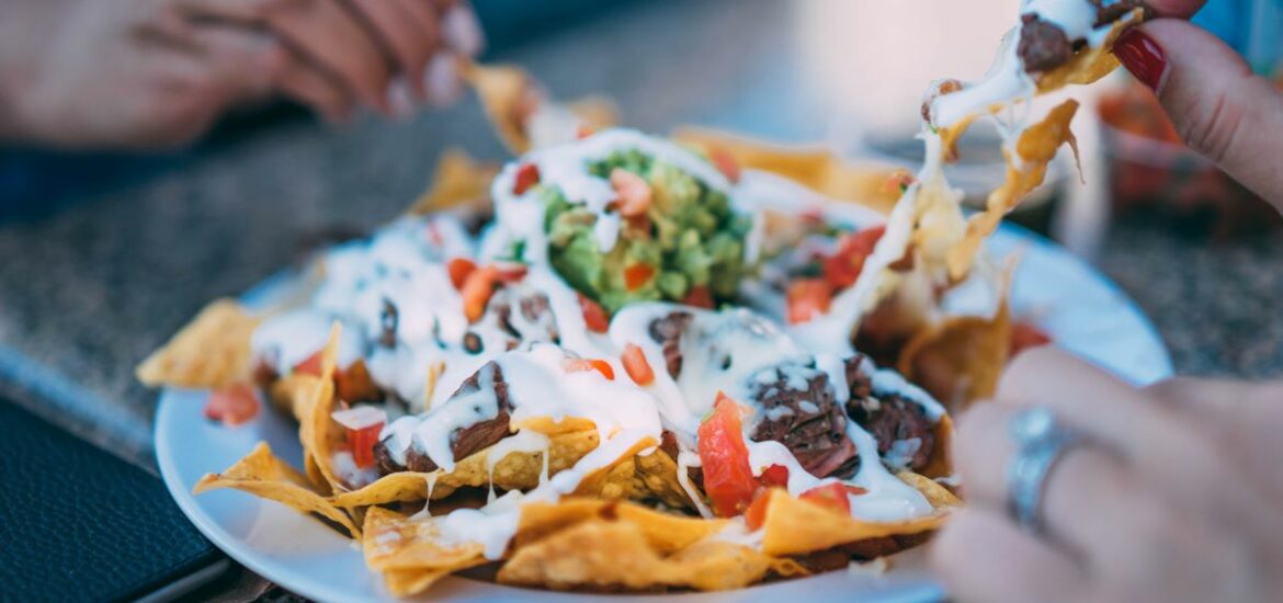 people grabbing nachos with cheese