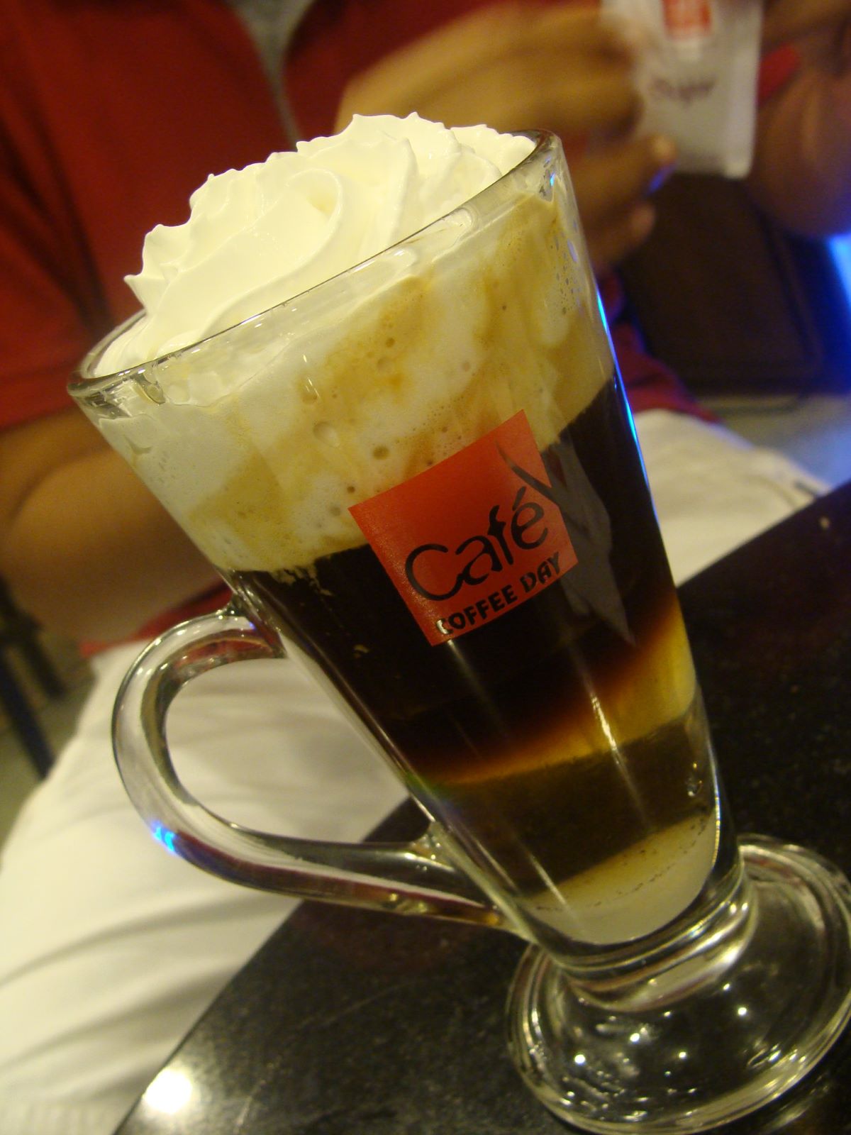 glass filled with brown liquid topped with whipped cream