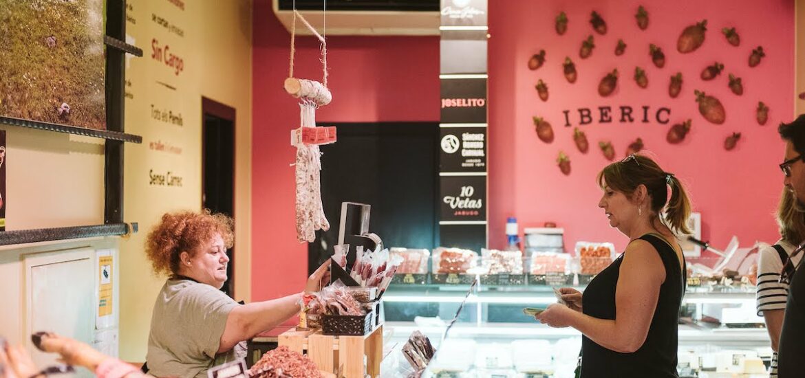 Woman purchasing cured ham at a deli shop.