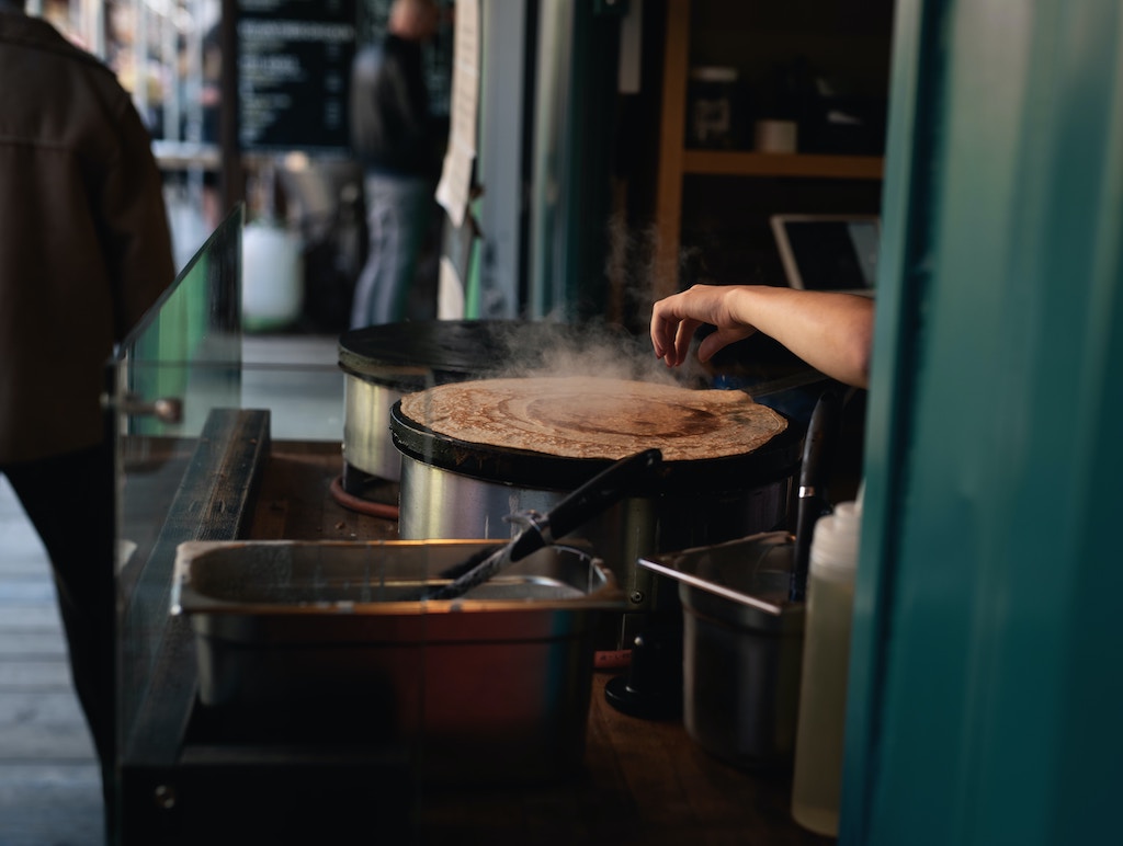 Street crepe stand with employee flipping crepe (pancake) from one side to the other