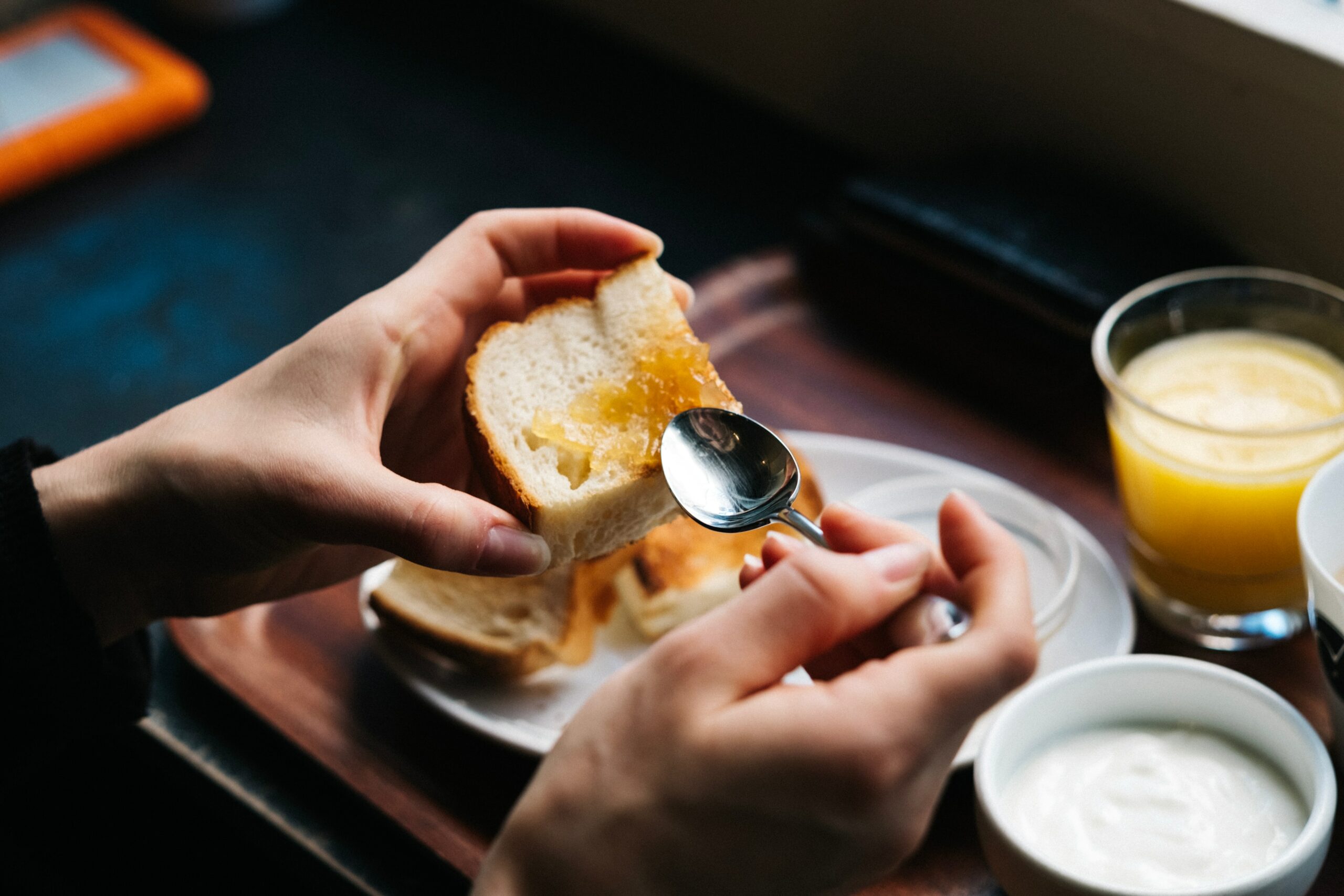 Person putting marmalade on toaste on toast 