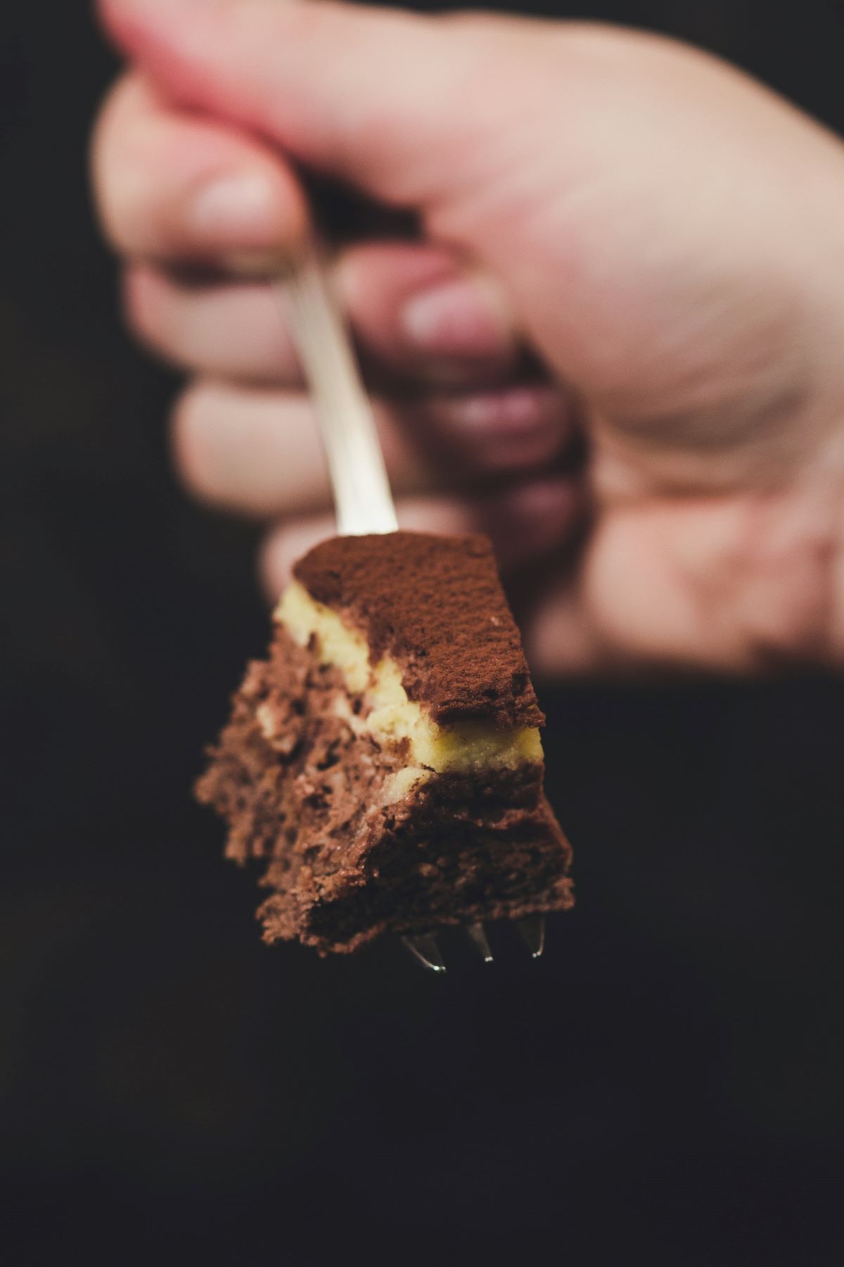 A person scooping up a bite of a piece of cake. 