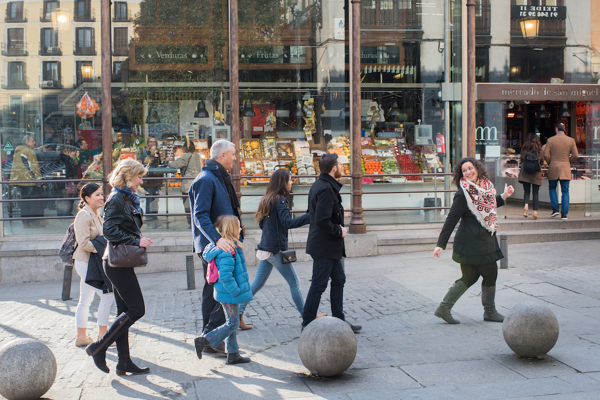 A guide leading a family on a food tour in front of the Mercado de San Miguel in Madrid