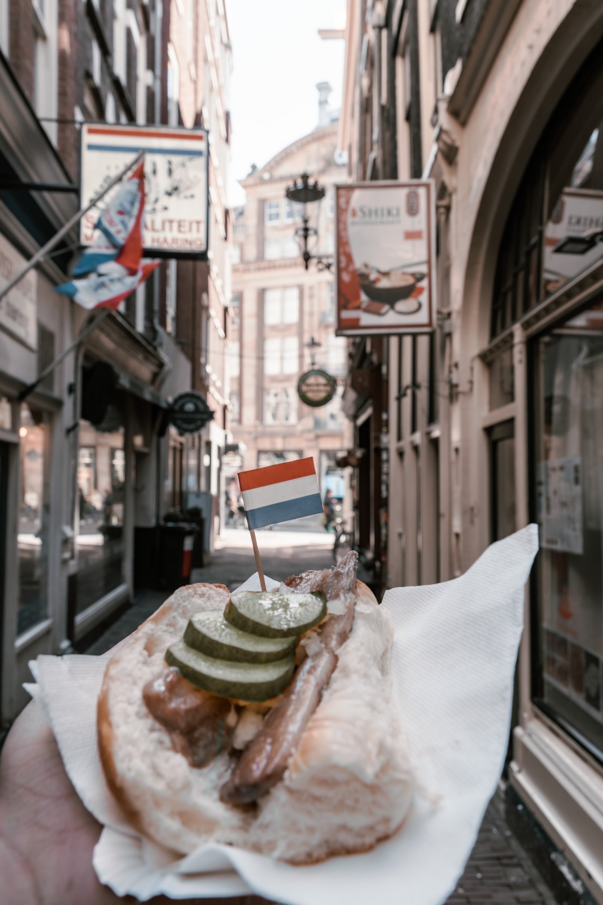 Herring on bread in a wrapper with Dutch flag outside on an Amsterdam street