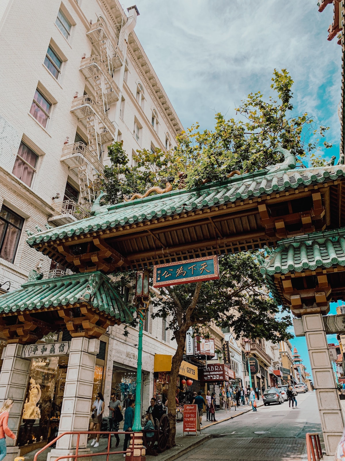 The green and white Dragon Gate at the entrance of Chinatown in San Francisco, with a blue sky with wispy white clouds above