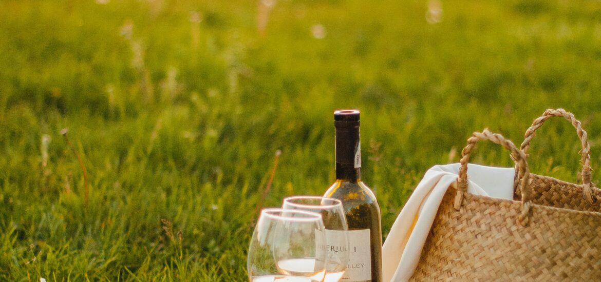 A bottle of wine and some bread sitting on the grass at a picnic