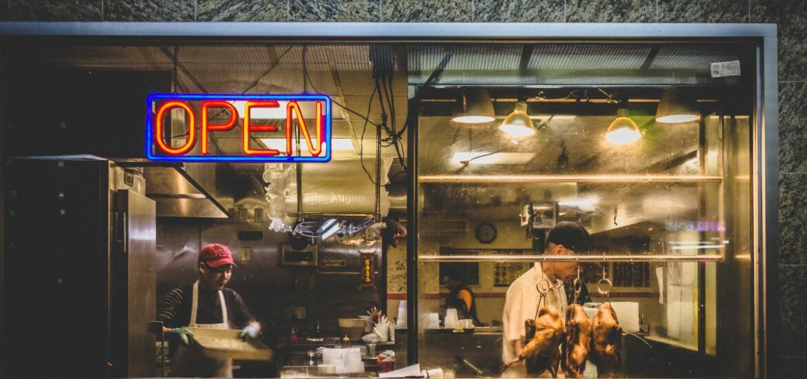 men cooking inside restaurant with neon light