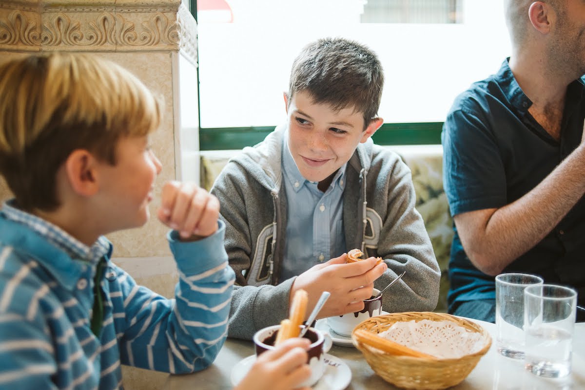 Two young boys eating churros at a cafe