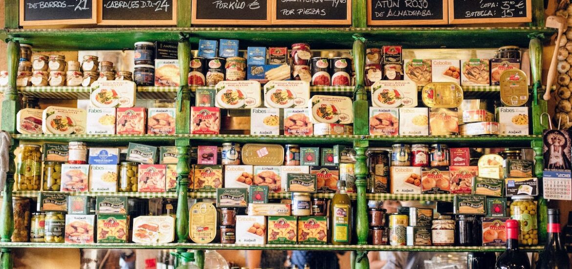 Shelf stocked with various food products at a small shop in Spain