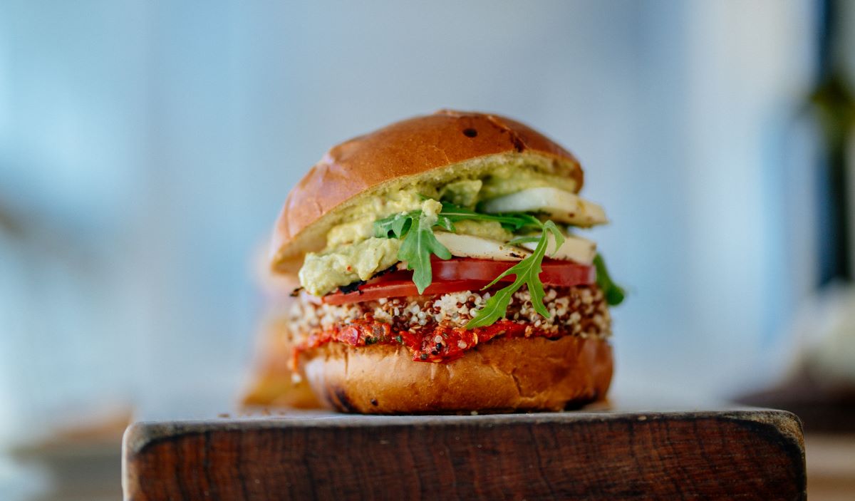 a veggie burger with peppers, quinoa, avocado and arugula