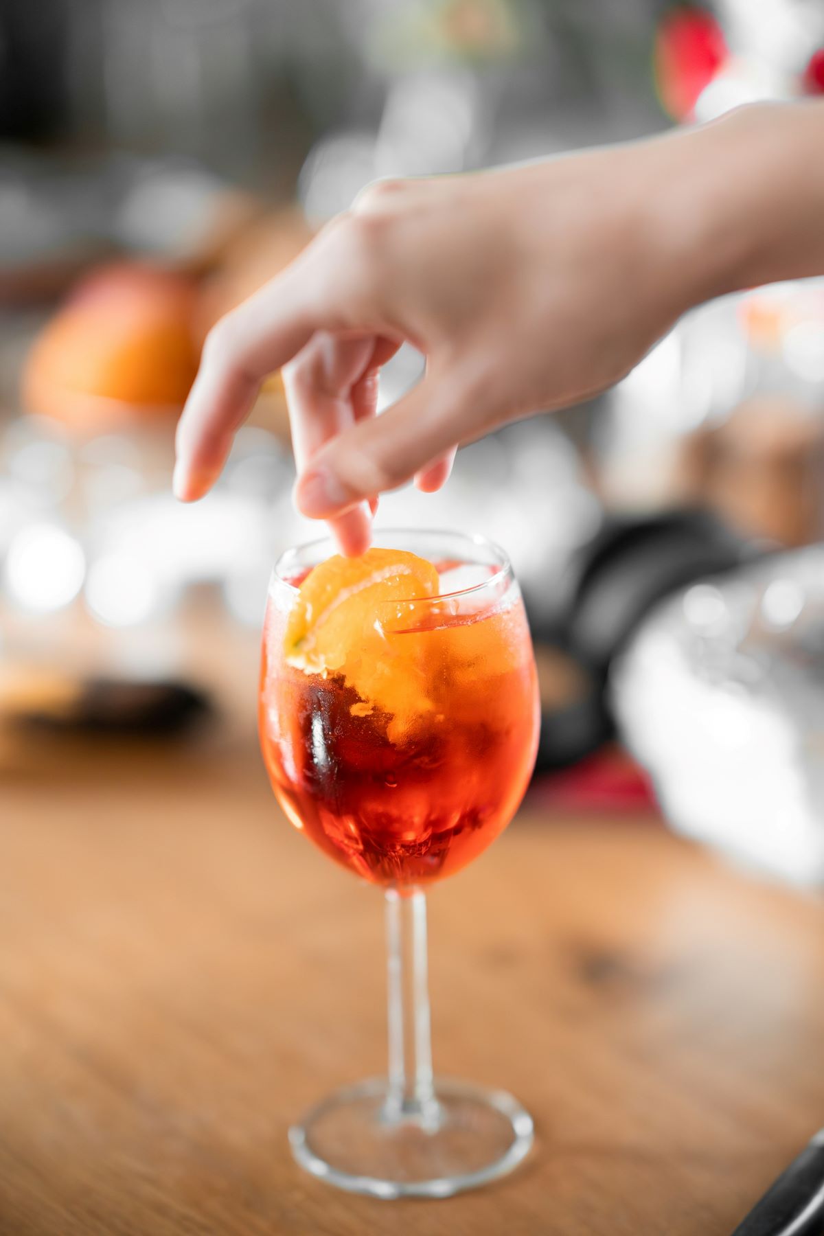 A person dipping an orange wedge into their Aperol spritz during their lunch in Madrid. 