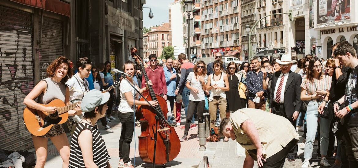 A crowd of people gathered around to watch a band of street performers play.