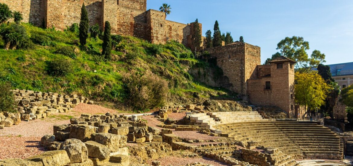 View of Roman amphitheater at the base of a Moorish stonewall fortress on a sunny day