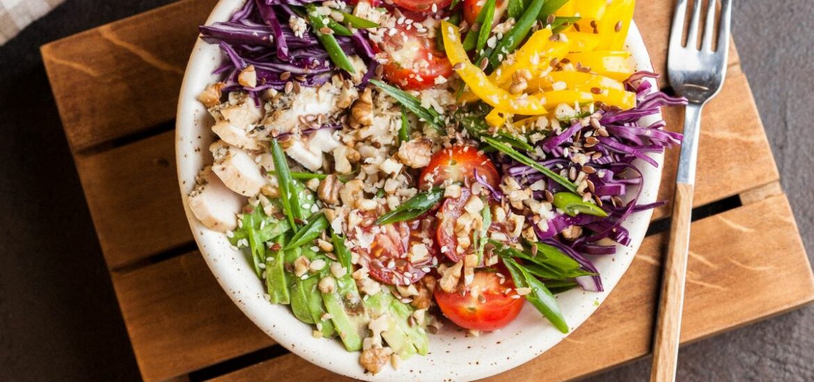 A colorful plate of different veggies including peppers, tomatos, mushrooms, cabbage, and avocado