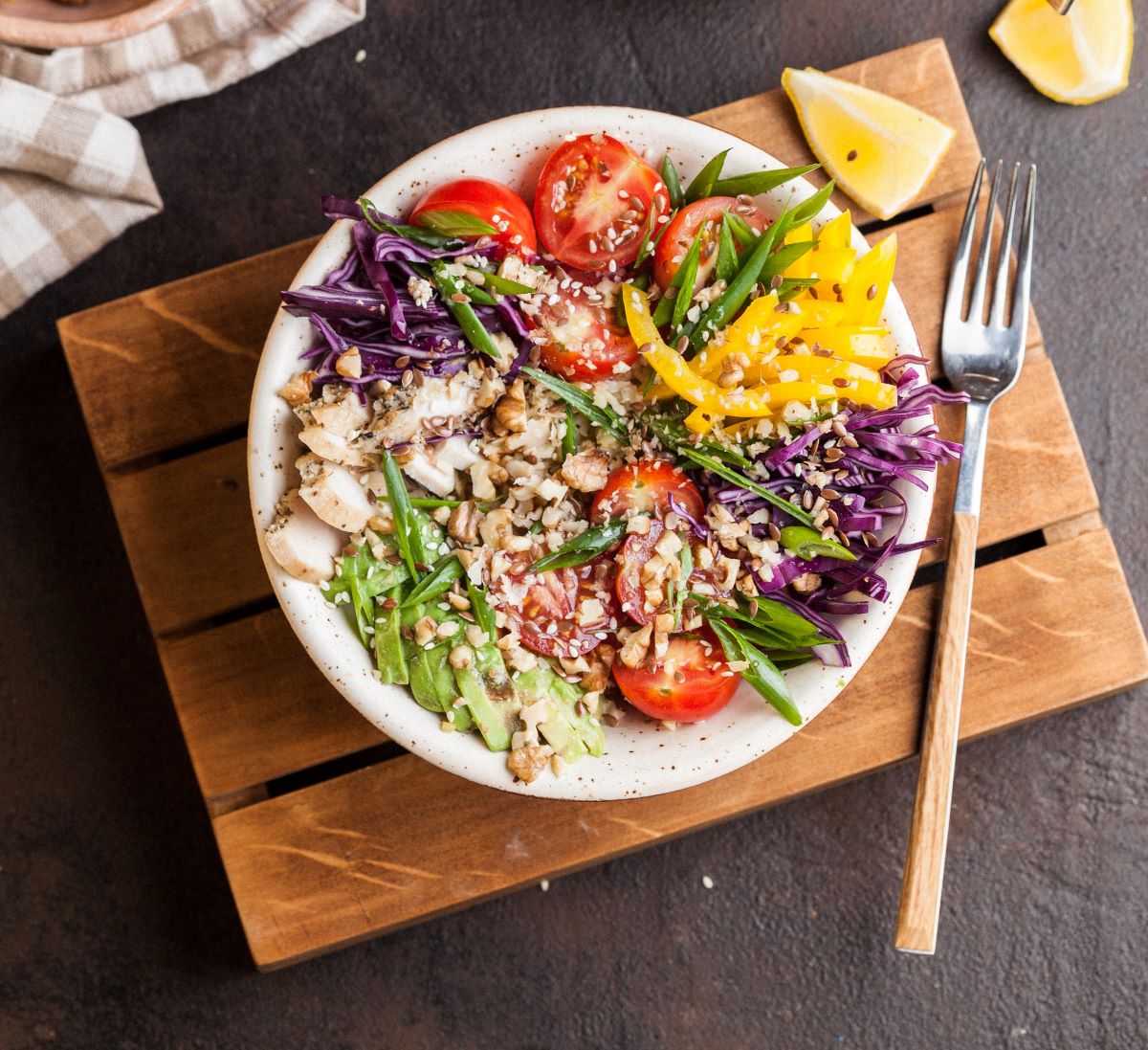 A colorful plate of different veggies including peppers, tomatos, mushrooms, cabbage, and avocado