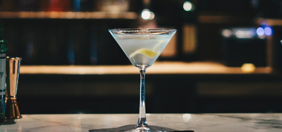 Martini garnished with a lemon peel on a bar top