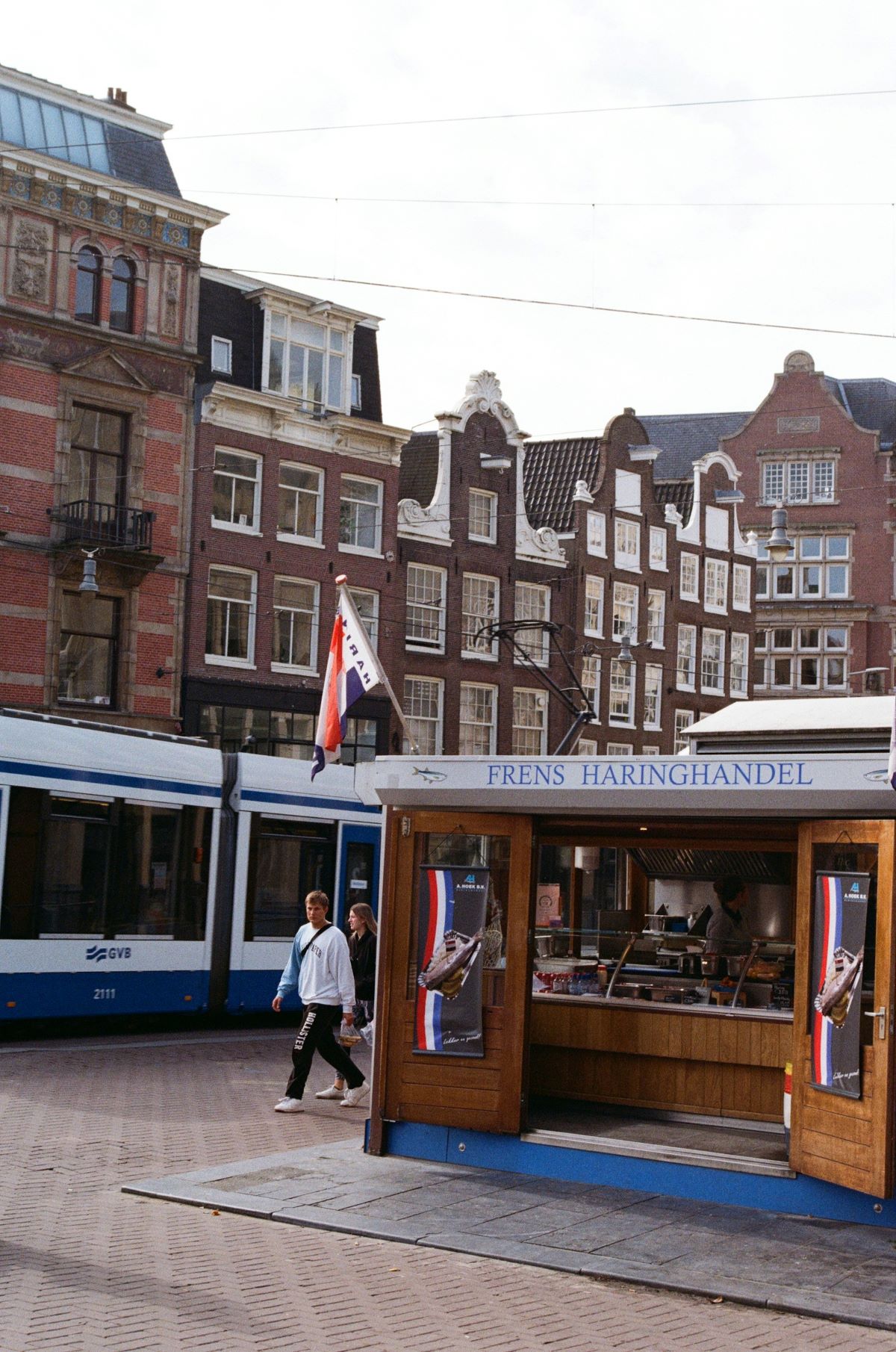 People walking past Frens Haringhandel stand. 