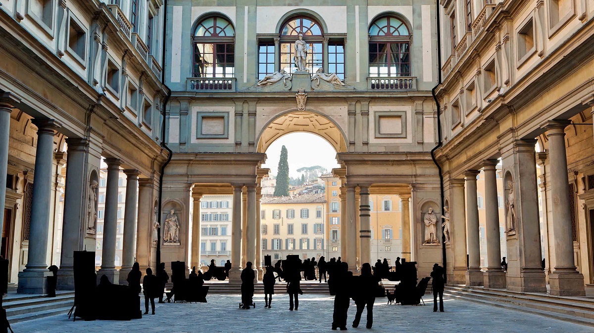 Old urban building with fancy windows and columns and a courtyard with people walking