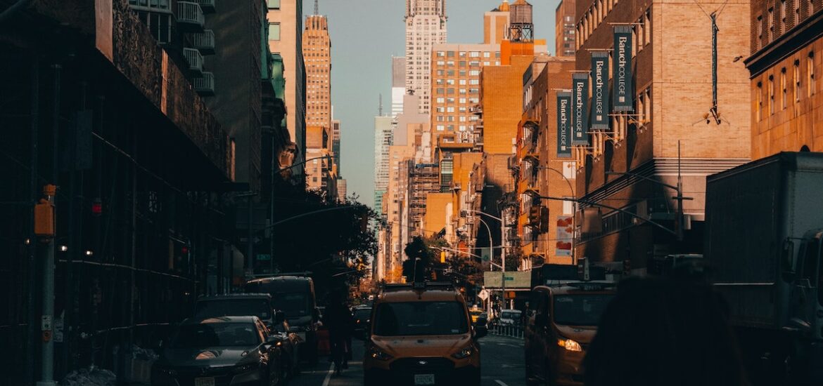 Busy city street in Midtown Manhattan with a tall skyscraper in the background