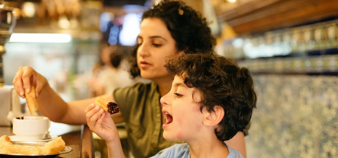 A child and his mother eating churros and chocolate