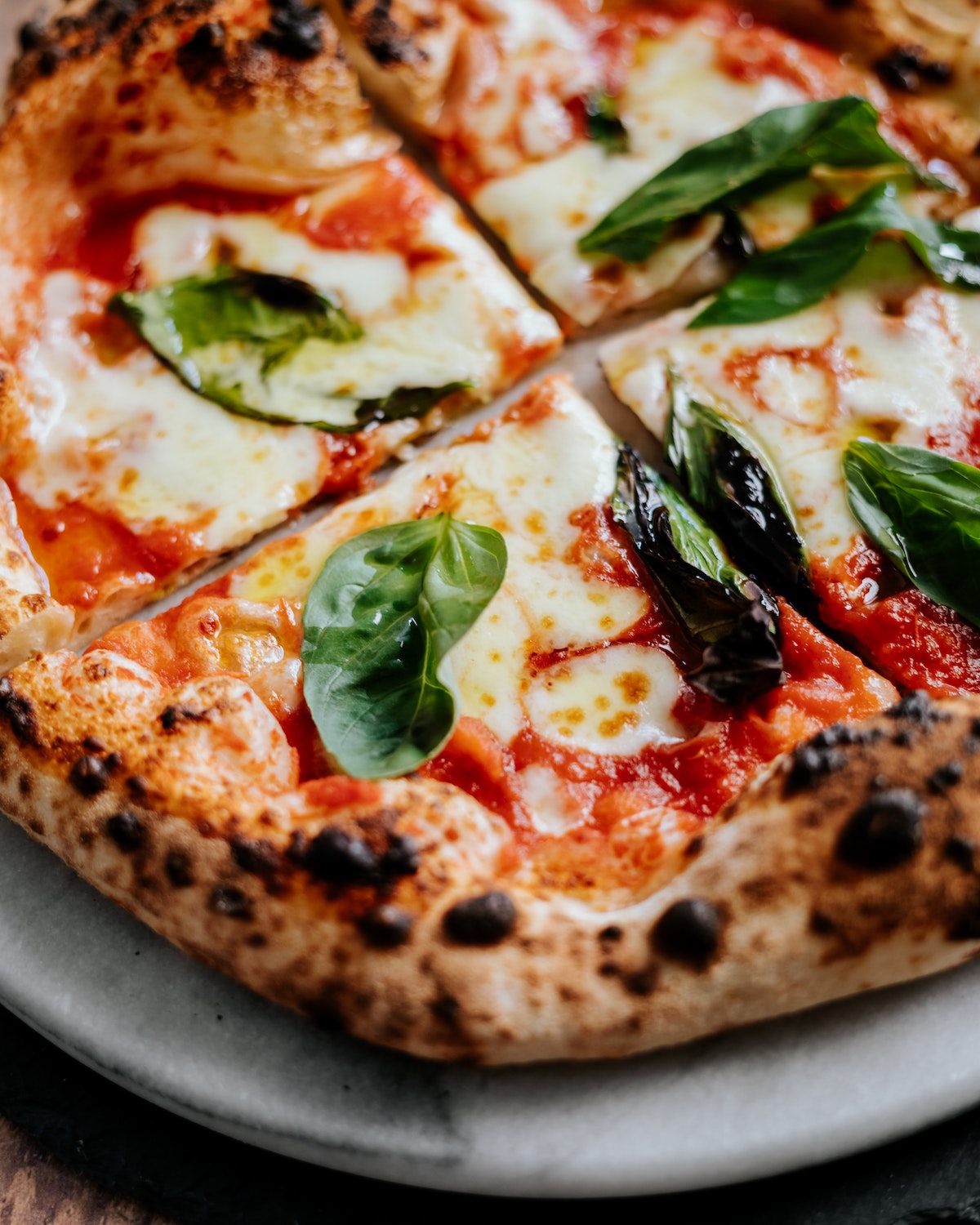 Close up of Neapolitan margherita pizza garnished with fresh basil