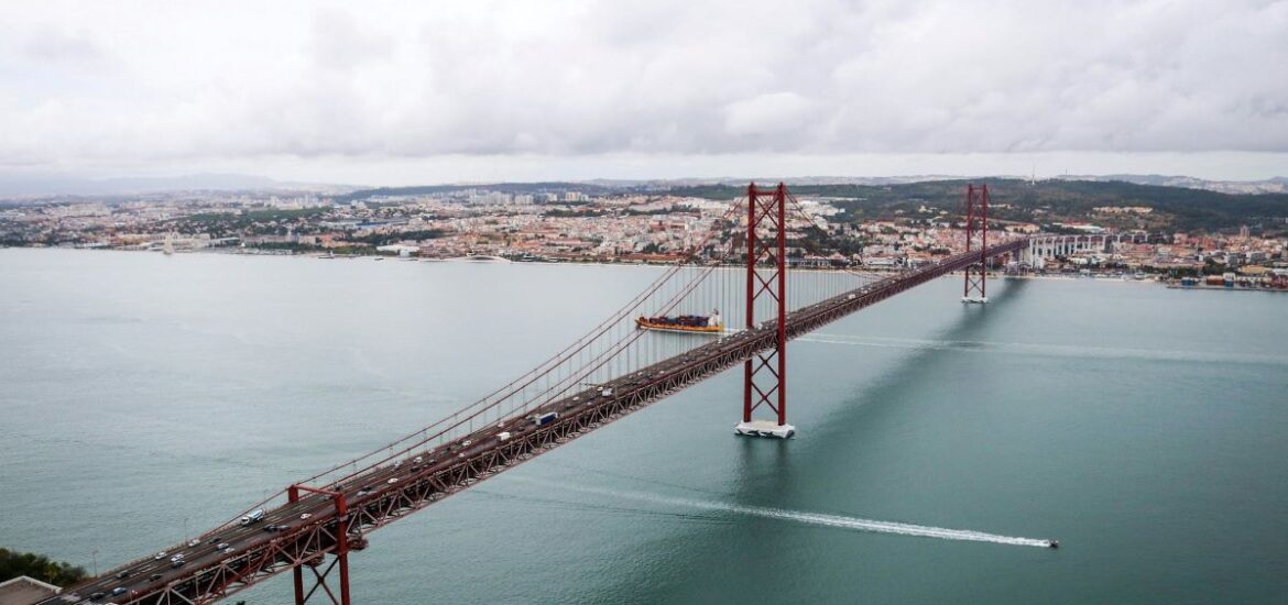 Ariel view of Lisbon's bridge in Fall as people drive across it.