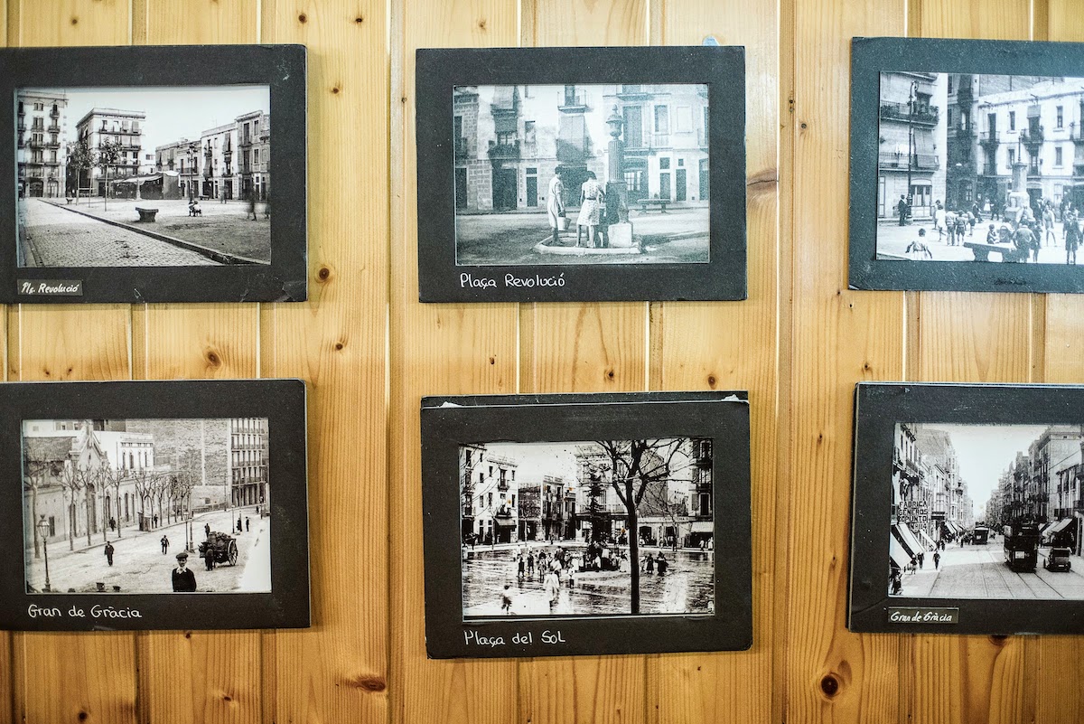 Old black-and-white photos of Barcelona hanging on a wood-paneled wall.