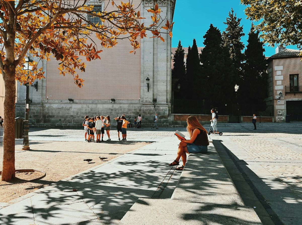 A woman sitting on steps reading a book in Madrid. 