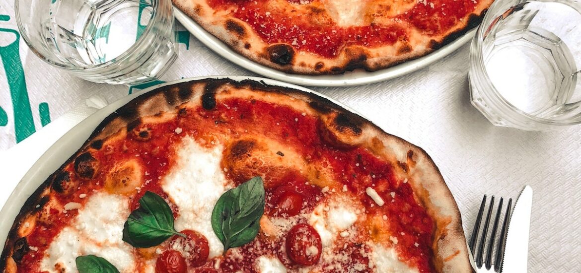 Overhead shot of two whole margherita pizzas with tomato, basil, and mozzarella cheese