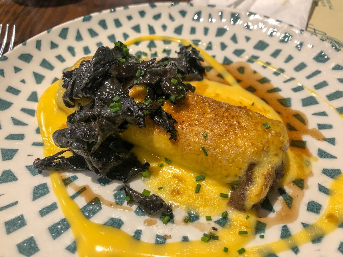 Oxtail cannelloni served with cooked leafy greens and a yellow sauce.