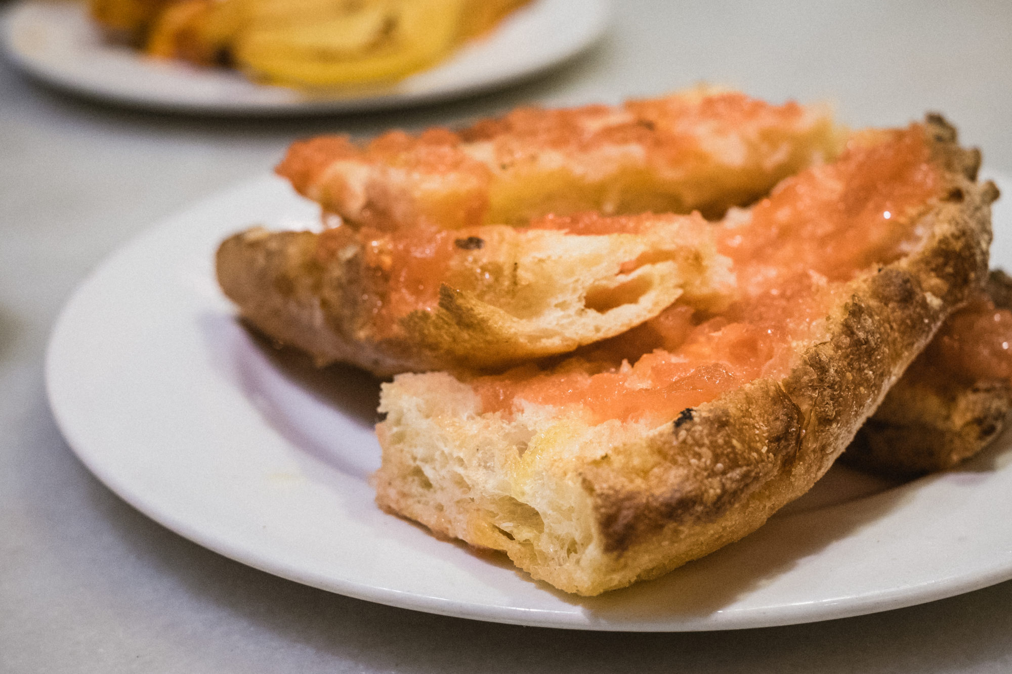 Slices of toasted bread rubbed with tomato on a white plate