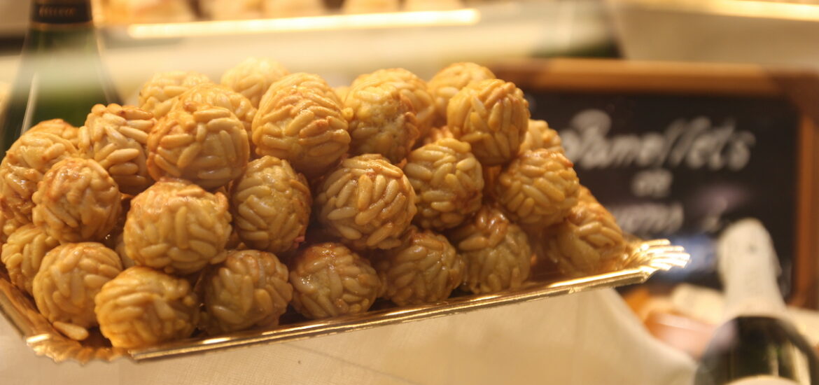Panellets (small ball-shaped sweets covered in pine nuts) on a thin golden tray