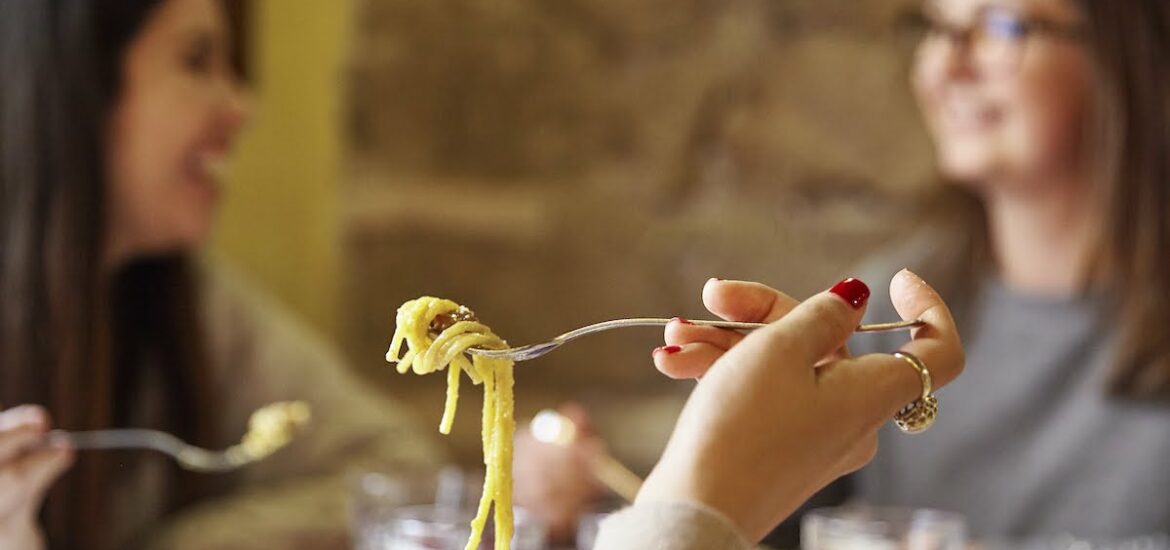 Close up of spaghetti on a fork in someone's hand