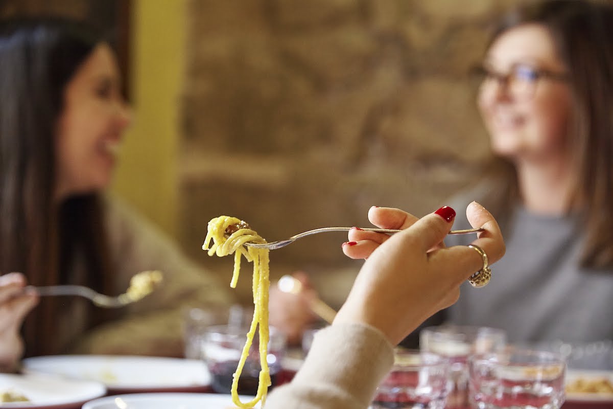 Close up of spaghetti on a fork in someone's hand