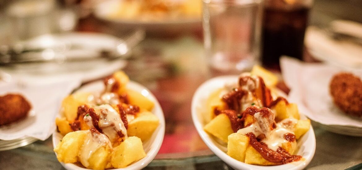 2 plates of patatas bravas and a glass of vermouth