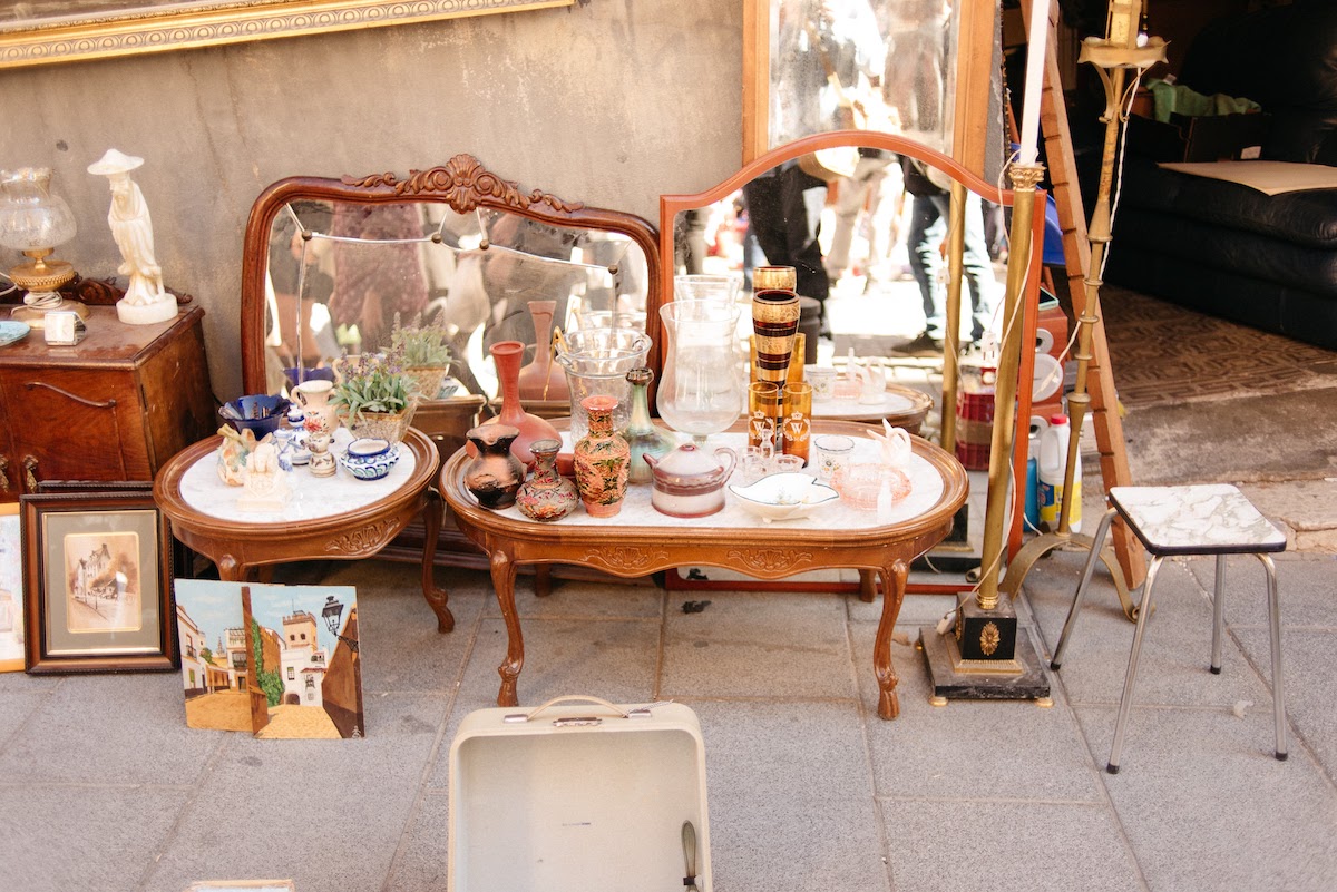Refurbished antiques including wooden furniture and mirrors on sale at a flea market.