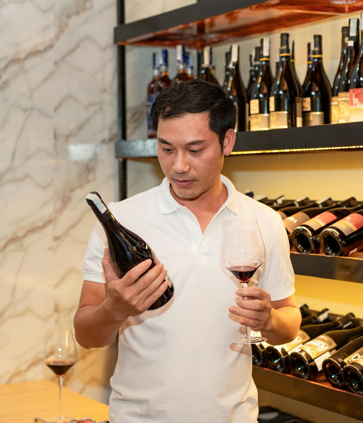 A man at a wine shop in Lisbon figuring out which bottle to select. 