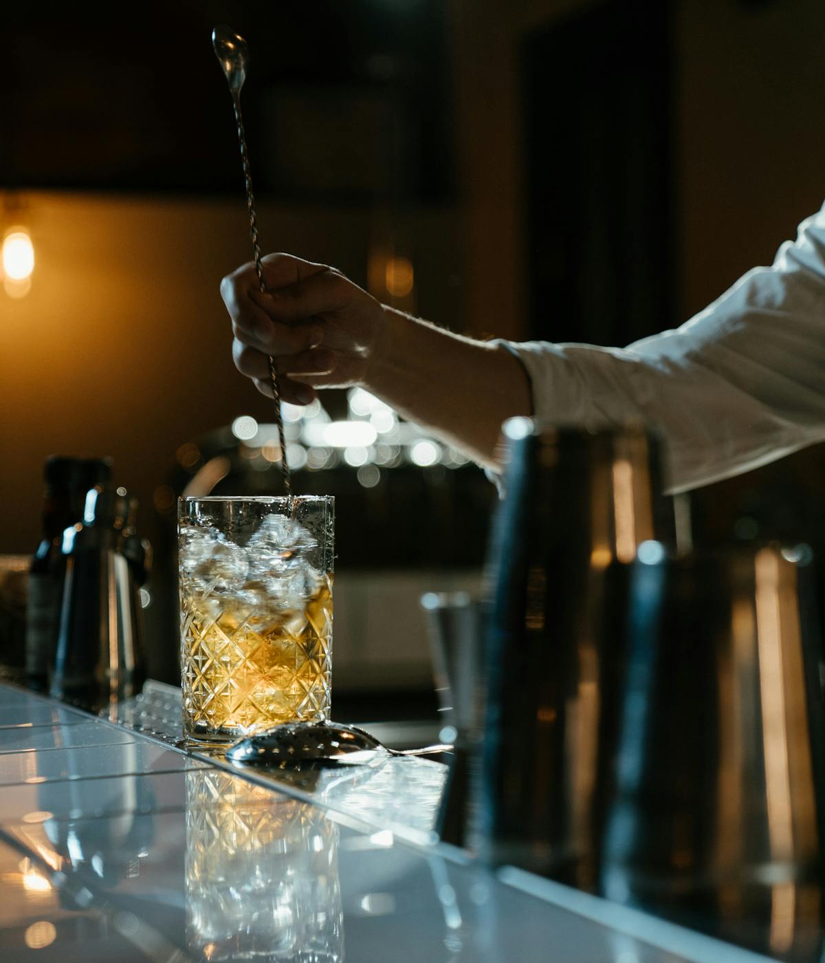 A darkly lit speakeasy as a bartender makes a drink at Bordeaux speakeasies. 