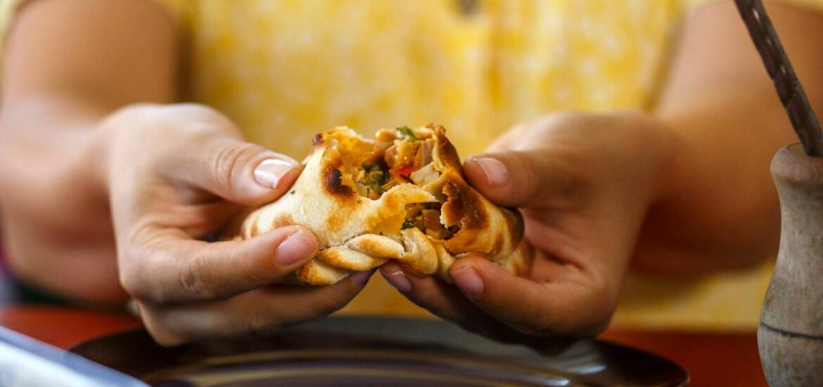 A woman in a yellow dress holding an empanada in NYC.