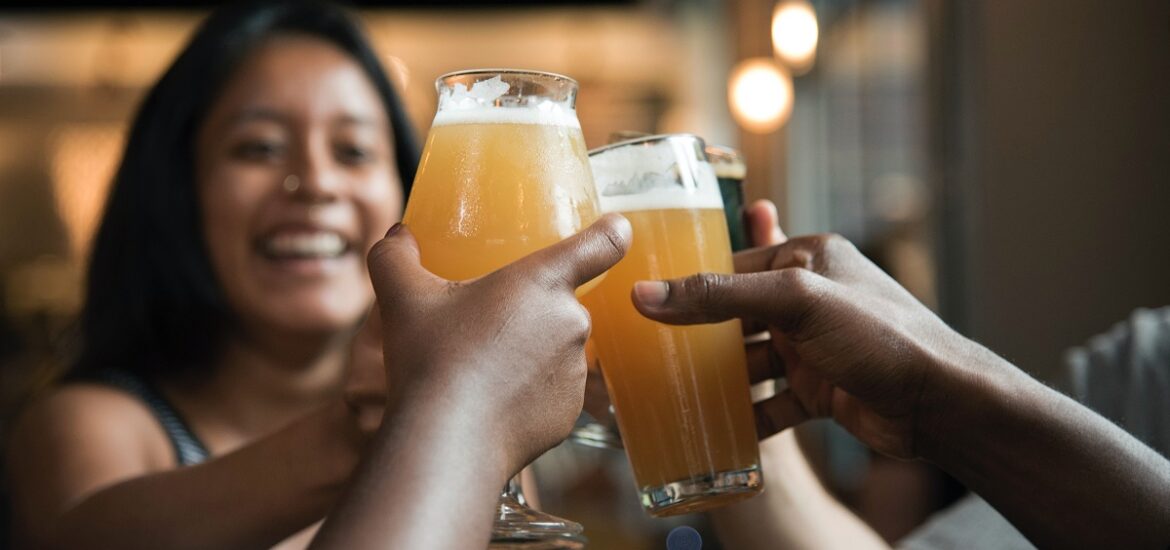 Smiling women holding up beer mugs and glasses for a cheers