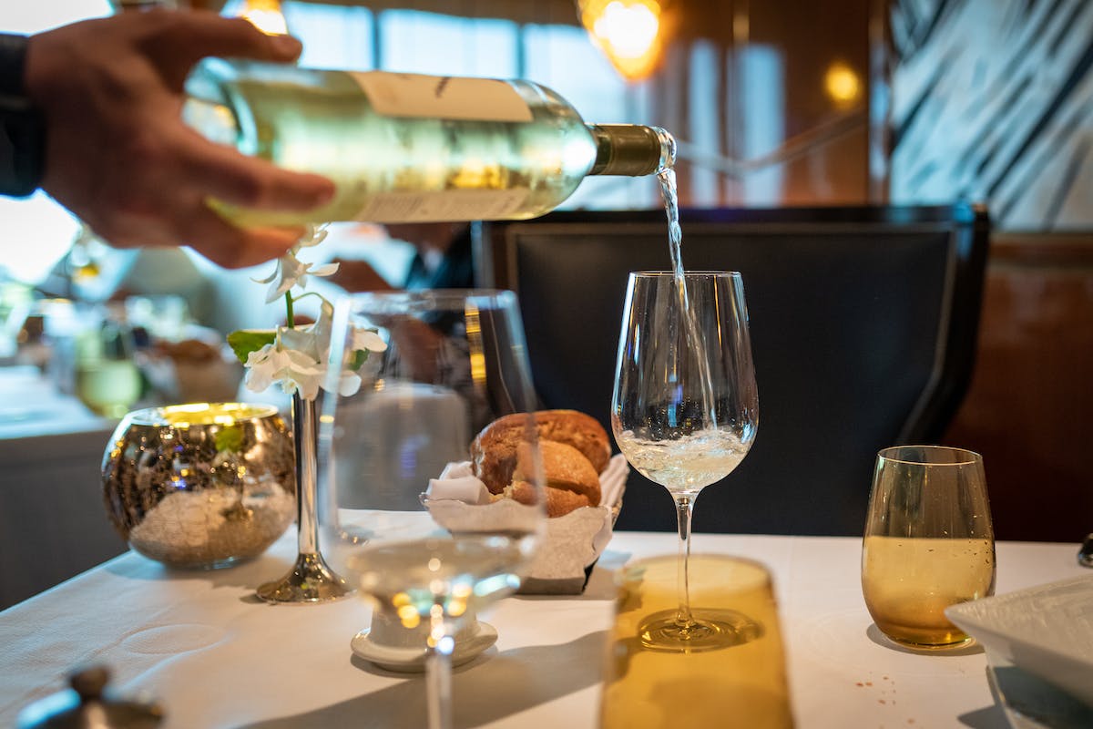 white wine bottle being poured on a glass