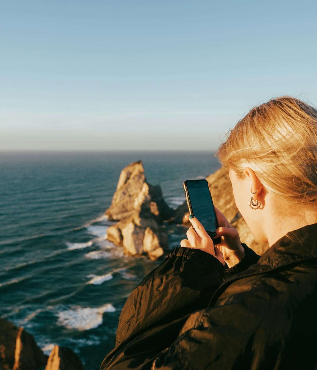 A woman taking a photo of the ocean views. 