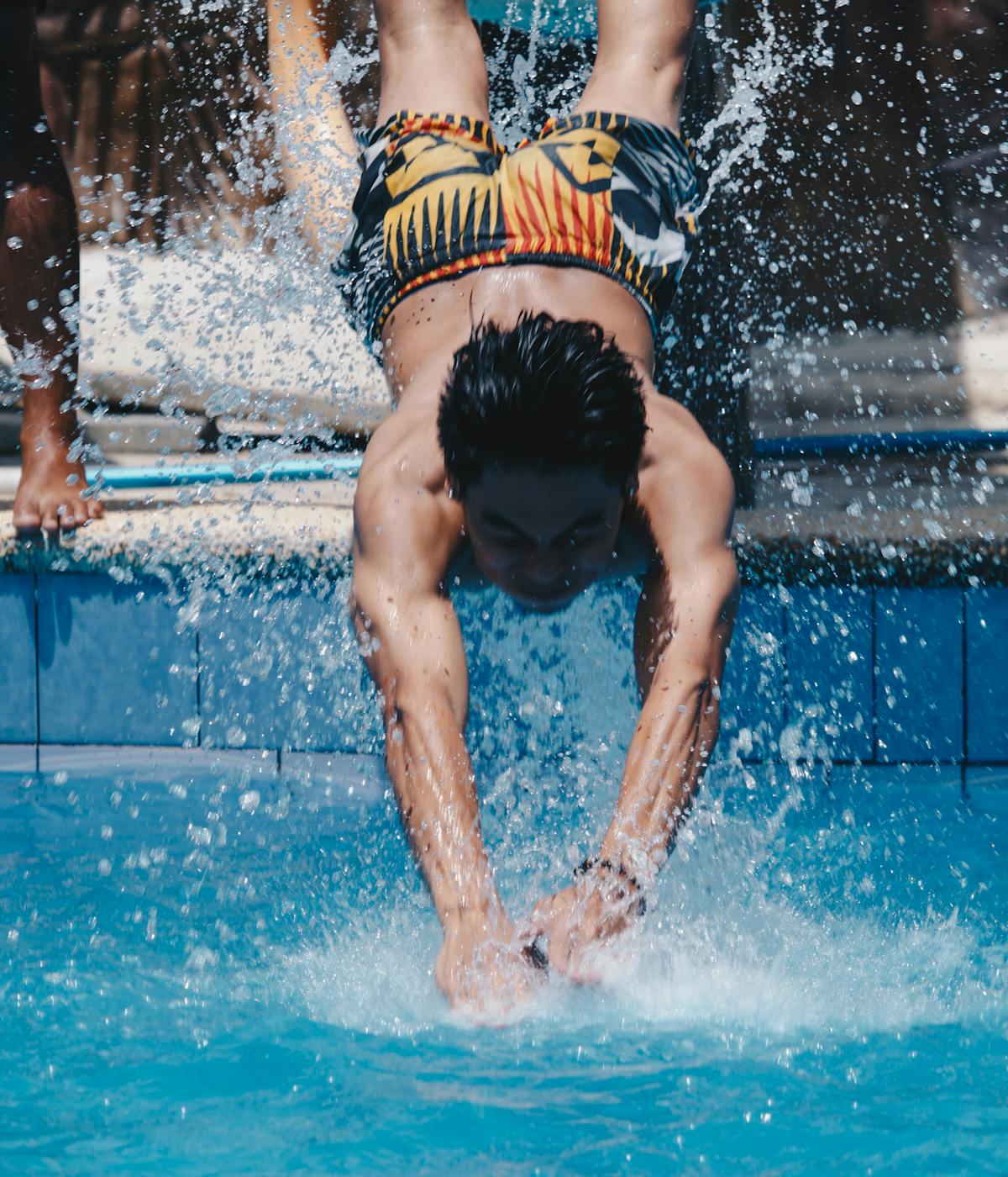 A boy going down a water slide head first into a pool 